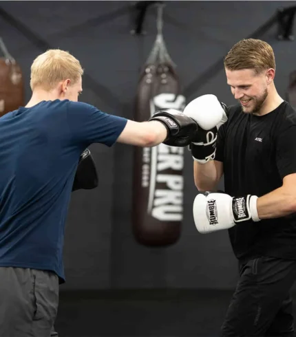 Trainer geeft handschoentraining aan een beginner tijdens de gratis proefles